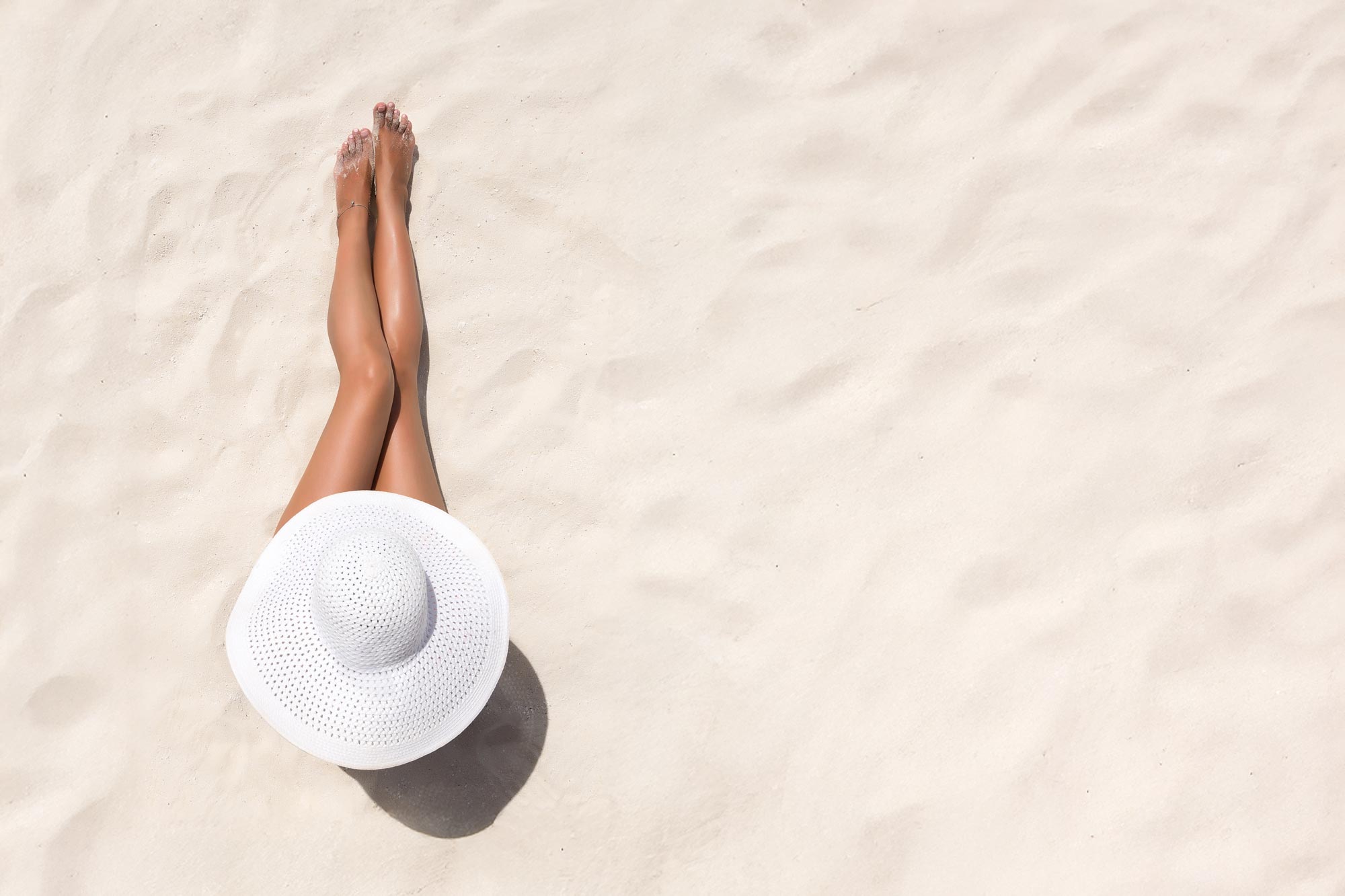 Kvinna med nyvaxade ben som sitter på en strand